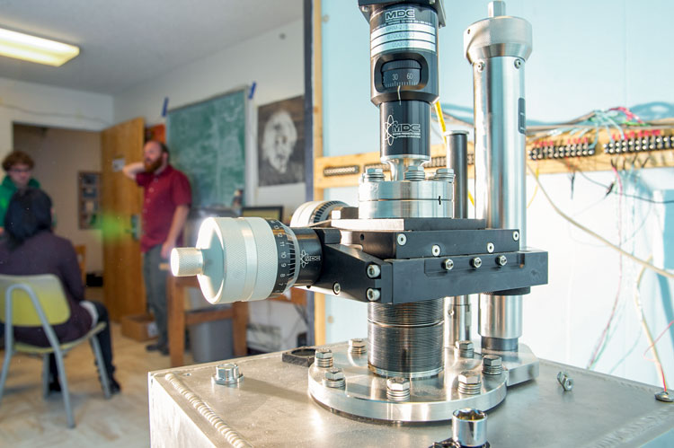 piece of equipment in the gravity lab with a professor and students blurred in the background